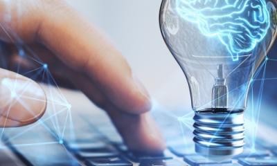 Hand typing on a computer with a brain icon in a lightbulb